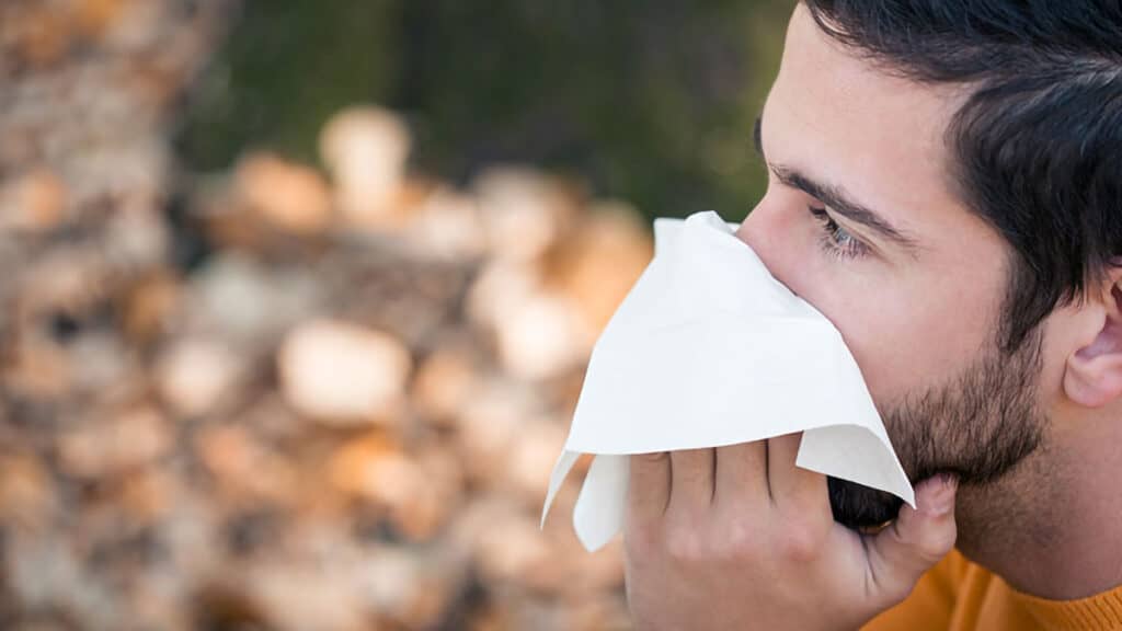 Man with allergies blowing nose