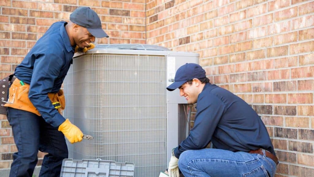 Two men repairing ac unit