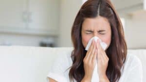 Woman sneezing into tissue