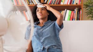 Woman using fan to cool down